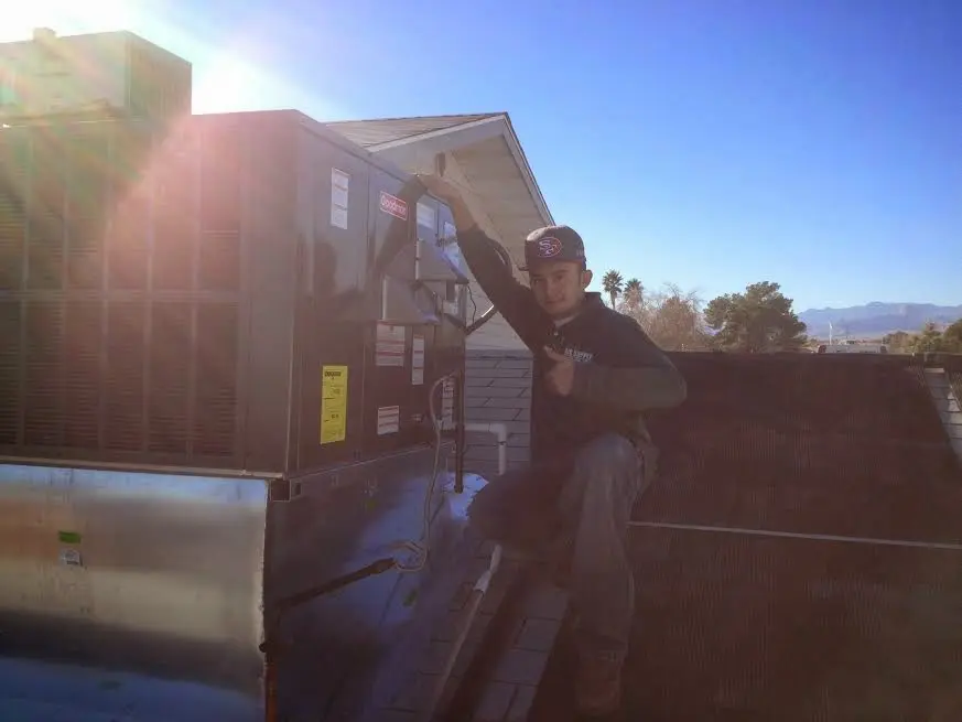 HVAC technician performing AC Tune-Up on a rooftop unit in Newport